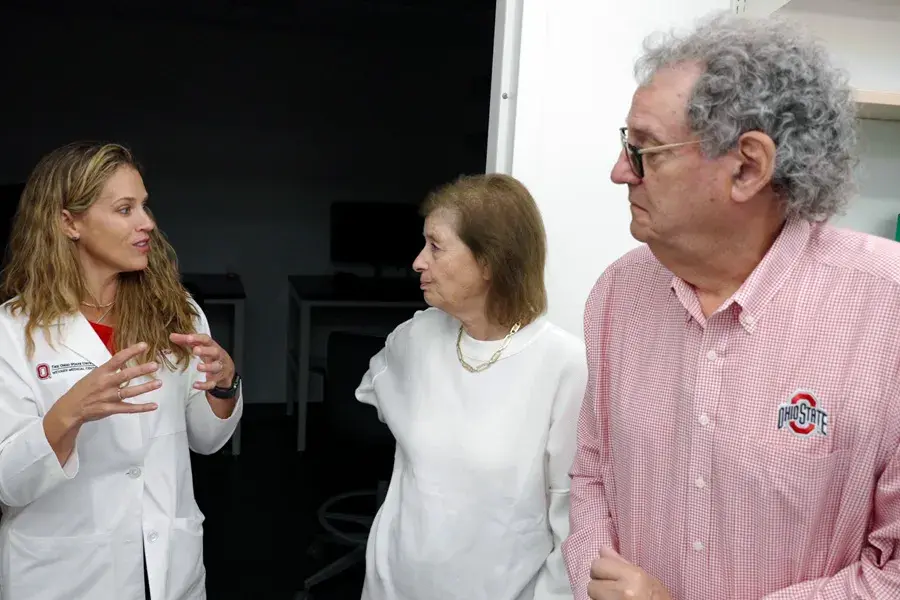 Two women and a man stand and talk to each other